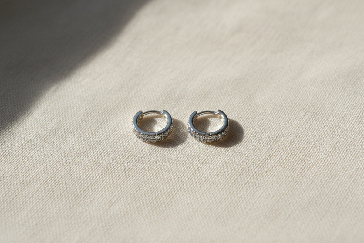 Sterling Silver Huggies — cream linen flatlay